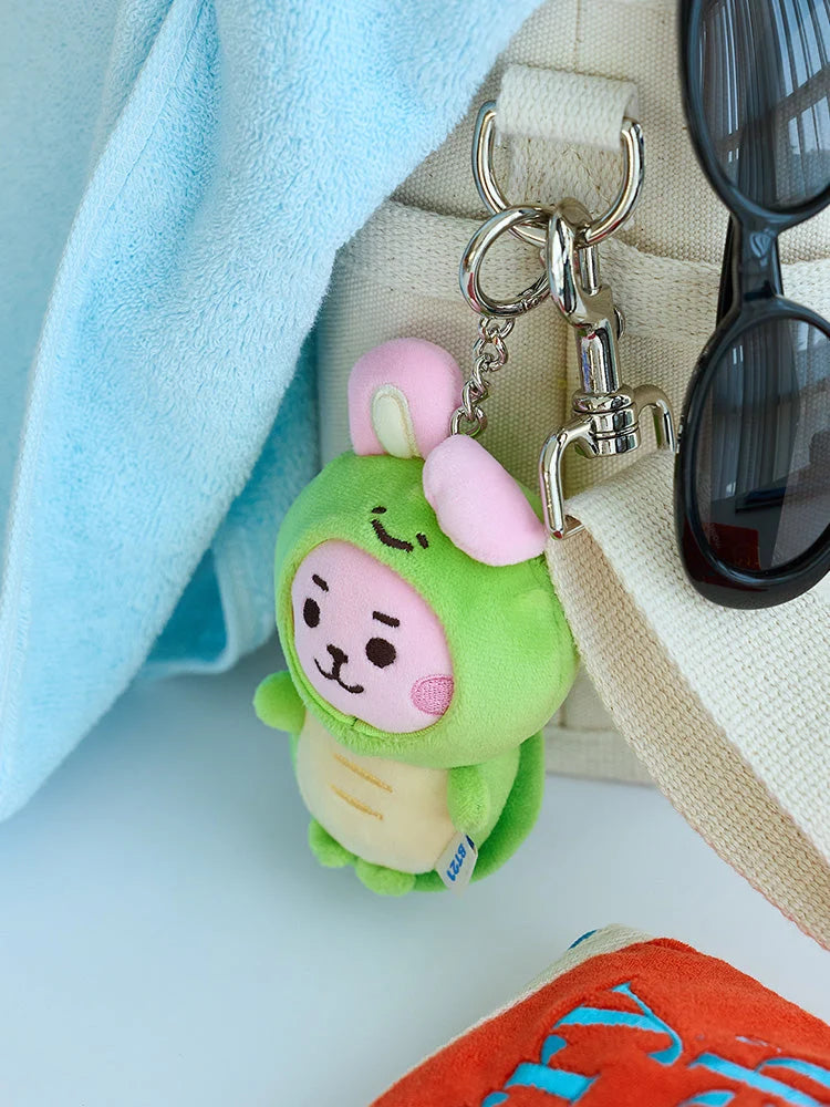BT21 COOKY BABY OCEAN FRIENDS mini doll keyring in a green sea-creature costume, shown attached to a bag