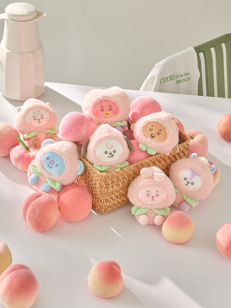 BT21 Peach Holic plush keyring character options arranged in and around a wicker basket with decorative peaches